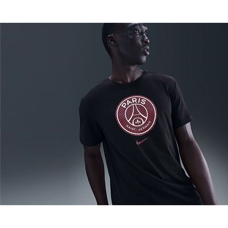 Vue de face d'un homme portant un t-shirt bleu Nike PSG avec le logo du club, à l'expression décontr