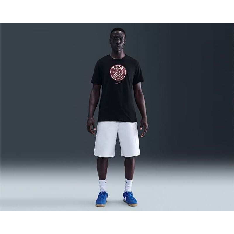 Vue de côté d'un homme portant un t-shirt bleu Nike PSG crest, montrant la coupe et la longueur des 