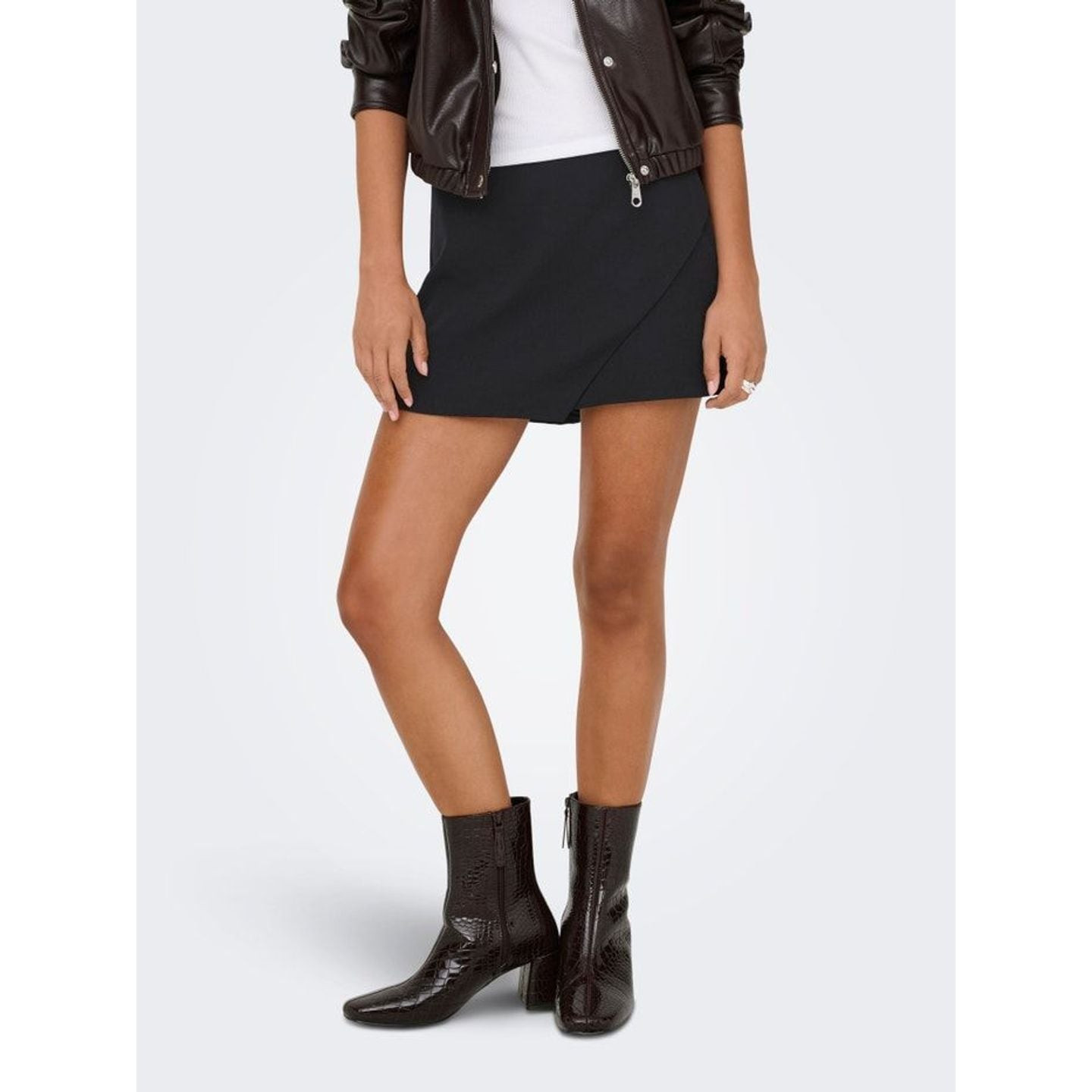 Mannequin portant le short-jupe enroulé ONLMIST Yasmine en noir, avec un haut et des talons.