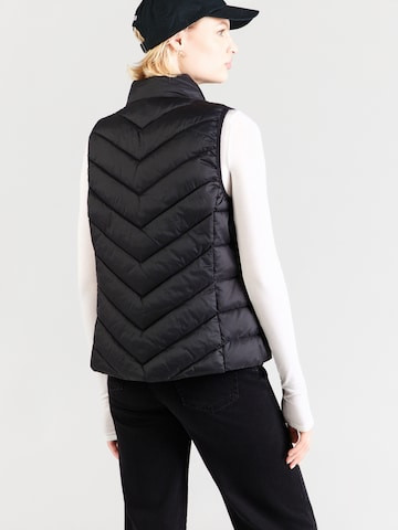 Woman wearing the ONLNEWCLAIRE black quilted vest in a casual outdoor lifestyle setting, layered ove