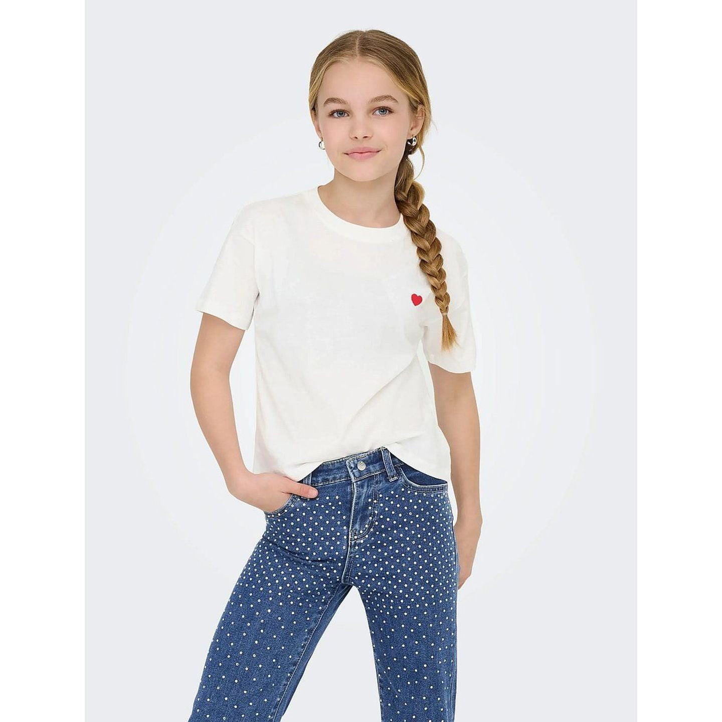 Image lifestyle d'une fille portant un t-shirt cropped rose Kids Only à broderie cœur, avec jean et 