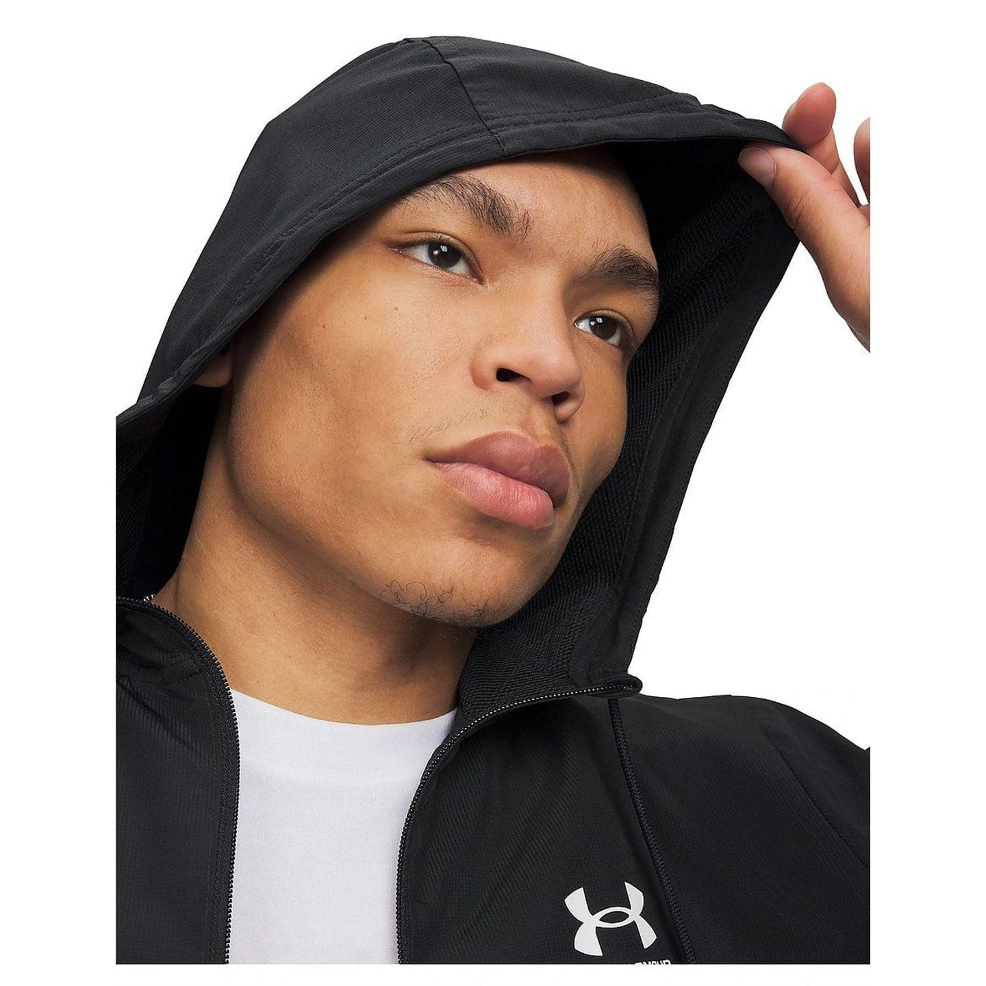 Photo lifestyle d'un homme en jogging extérieur avec la veste Under Armour UA Rival Woven, capuche r