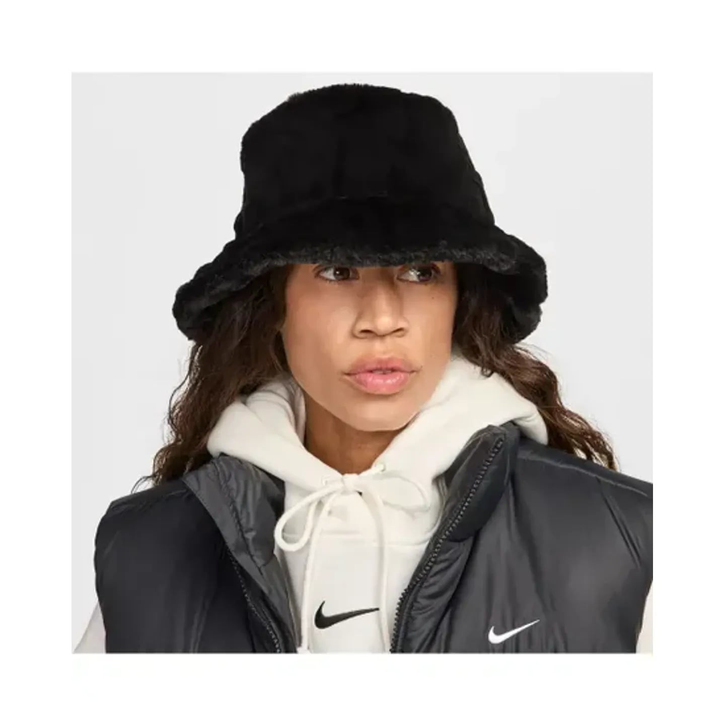 Vue de face d'un mannequin portant le bob Nike Apex en fausse fourrure noire avec hoodie crème et gi