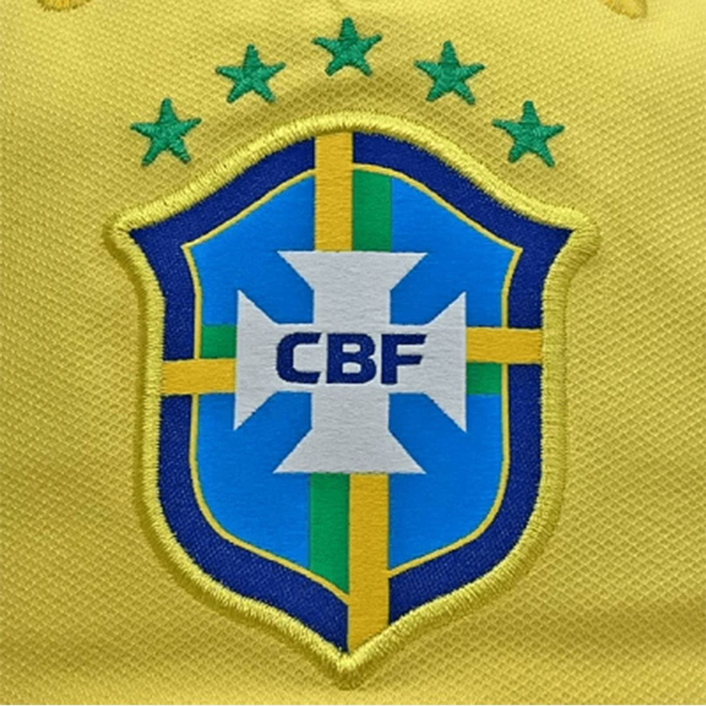 Gros plan sur l'écusson brodé CBF Brésil avec croix et cinq étoiles vertes sur casquette jaune