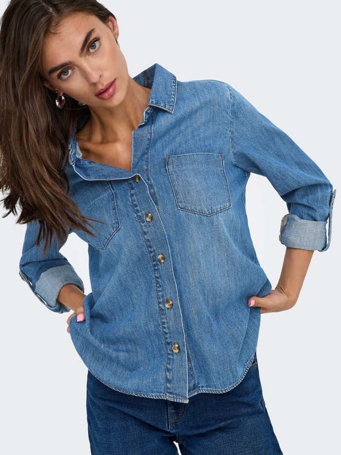 Model wearing ONLYASMIN blue denim shirt with hands in pockets styled as double denim casual look