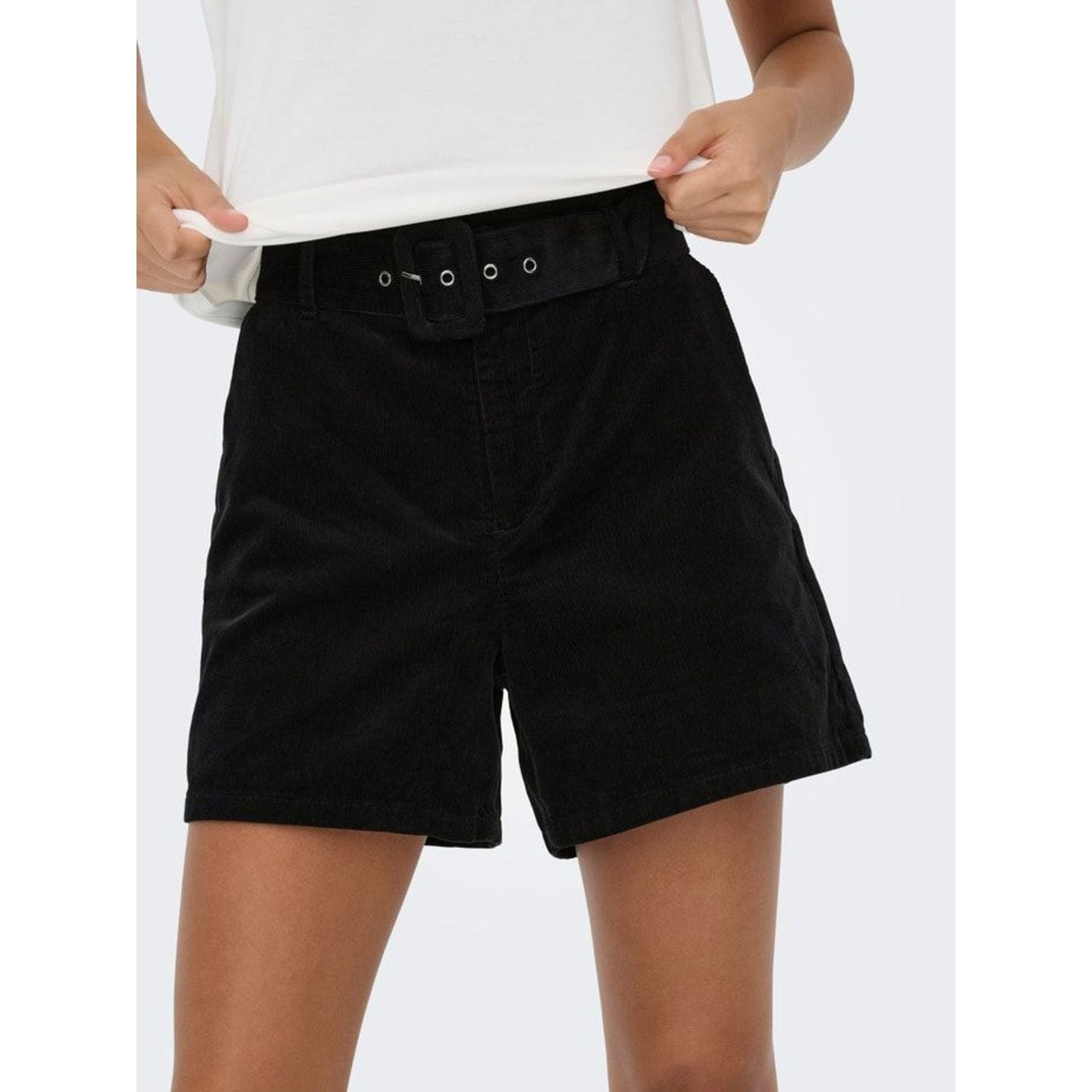 Mannequin ajustant la ceinture du short taille haute en velours côtelé noir ONLY ONLNESSA avec un t-