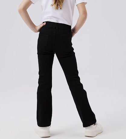 Back view of a girl wearing NAME IT NKFPOLLY black skinny boot jeans with white trainers