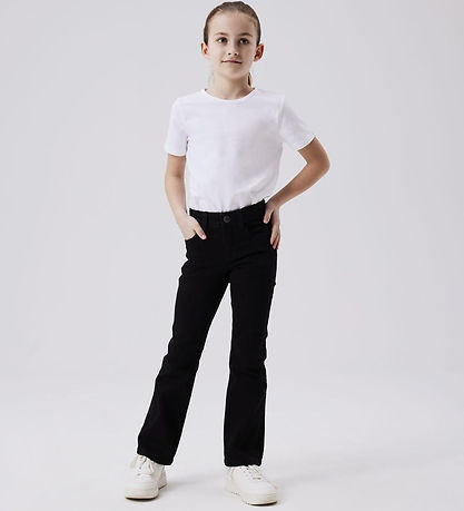 Girl standing with hands in pockets wearing NAME IT NKFPOLLY black boot-cut jeans and white tee