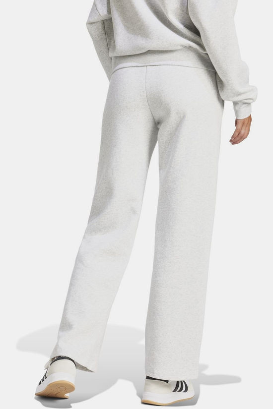 Lifestyle shot: woman stretching in Adidas Women's W SL FC PT Essentials Small Logo Fleece Pants