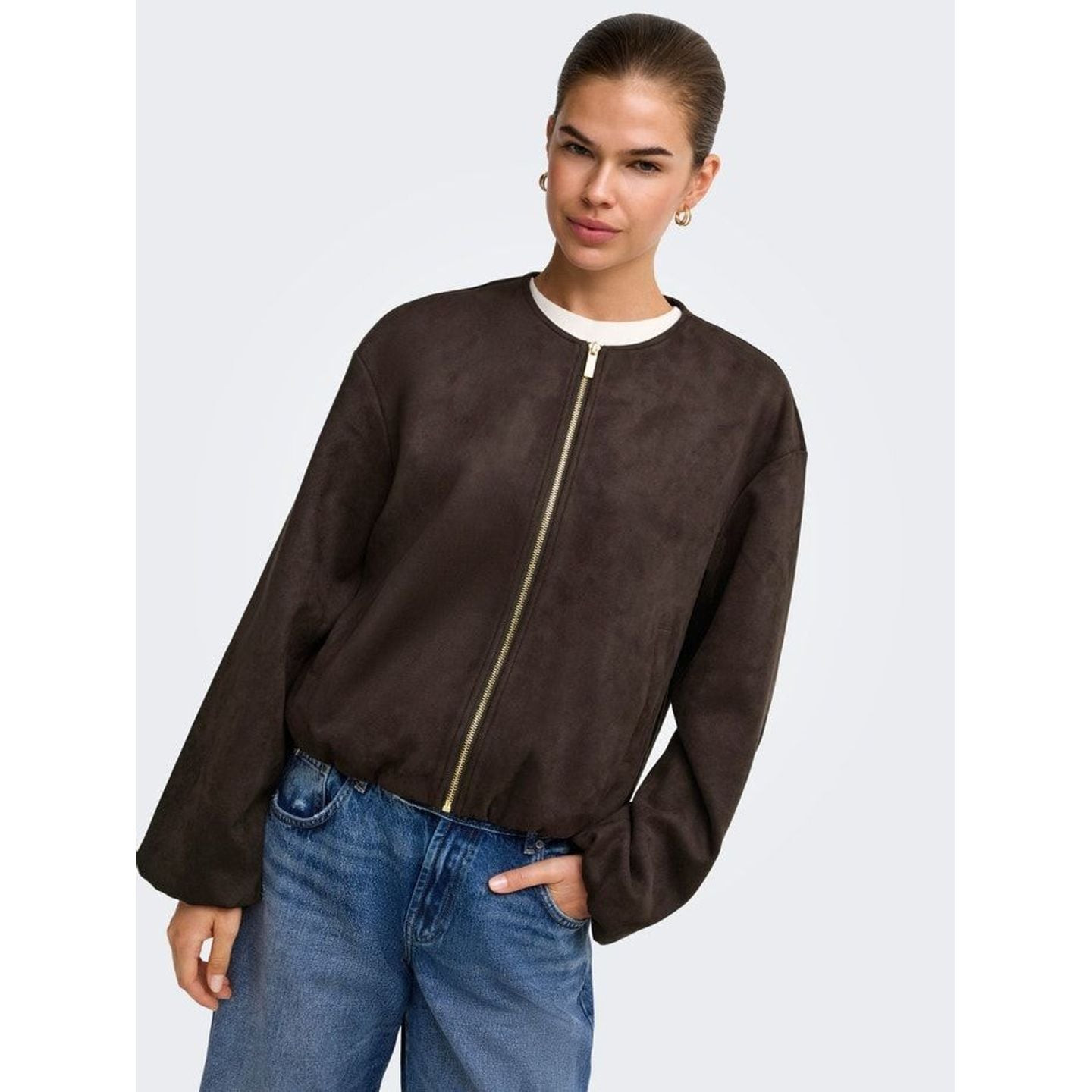 Femme en veste bomber en faux suède brun foncé, jean bleu et haut blanc, pour un look décontracté au