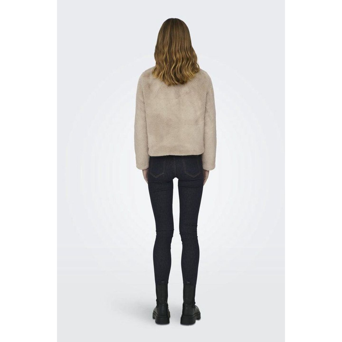 Mannequin de dos portant la veste courte en fausse fourrure beige, jean foncé et bottes noires