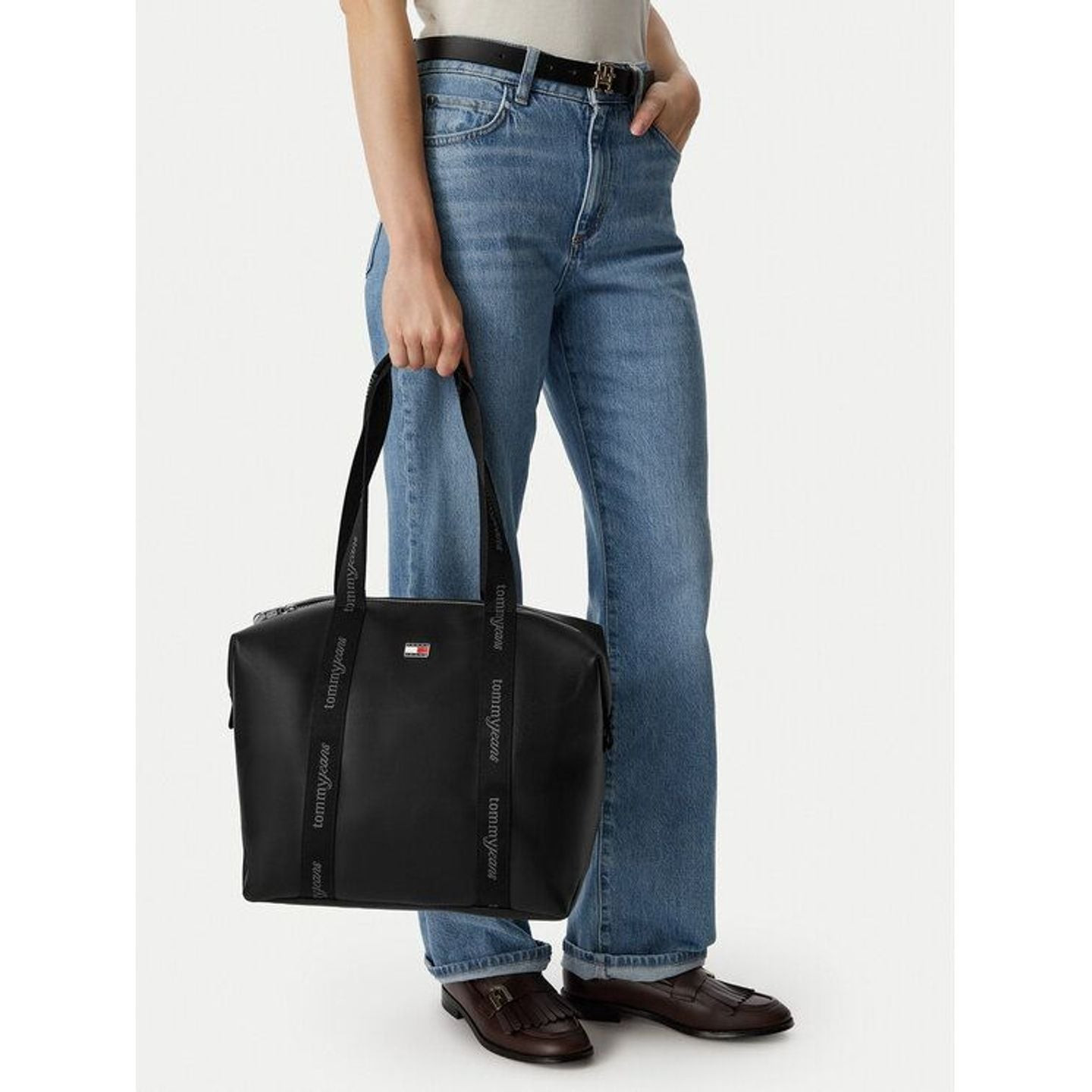 Femme en jean portant le sac tote noir Tommy Jeans à l'épaule