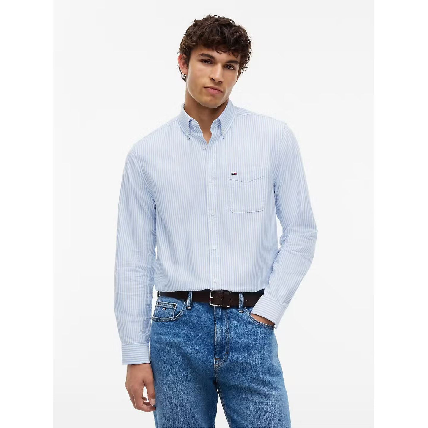 Homme portant la chemise Oxford Tommy Jeans coupe régulière à rayures bleues et blanches, mains dans