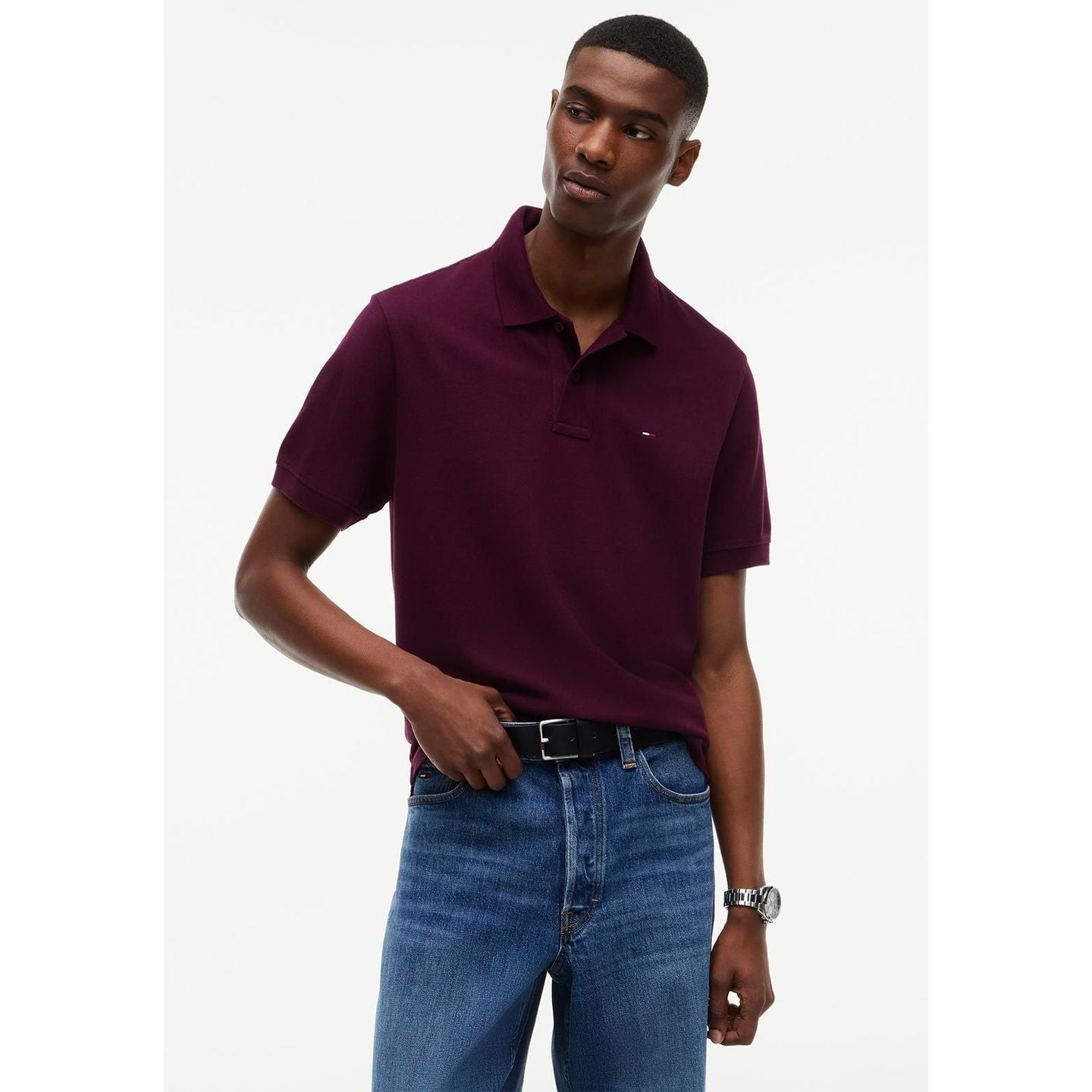 Mannequin portant le polo Tommy Jeans Purple Berry avec un jean bleu et une ceinture en cuir noir, e