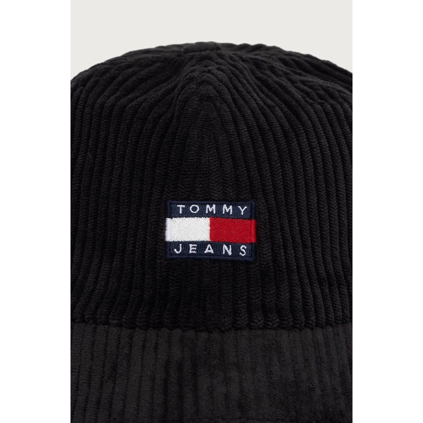Gros plan du logo drapeau Tommy Jeans brodé à l’avant de la casquette en velours côtelé noire.