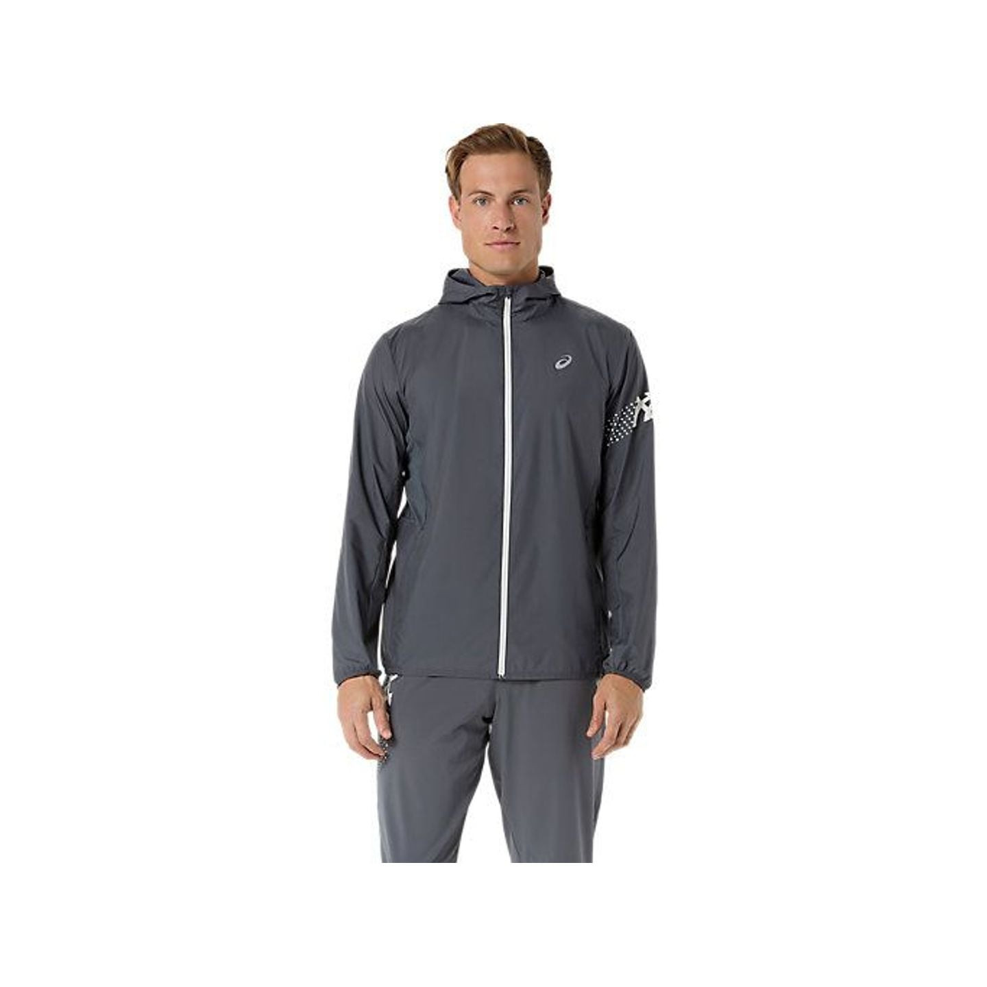L'ASICS Veste De Running Déperlante Icon Jacket Homme portée par un coureur en ville