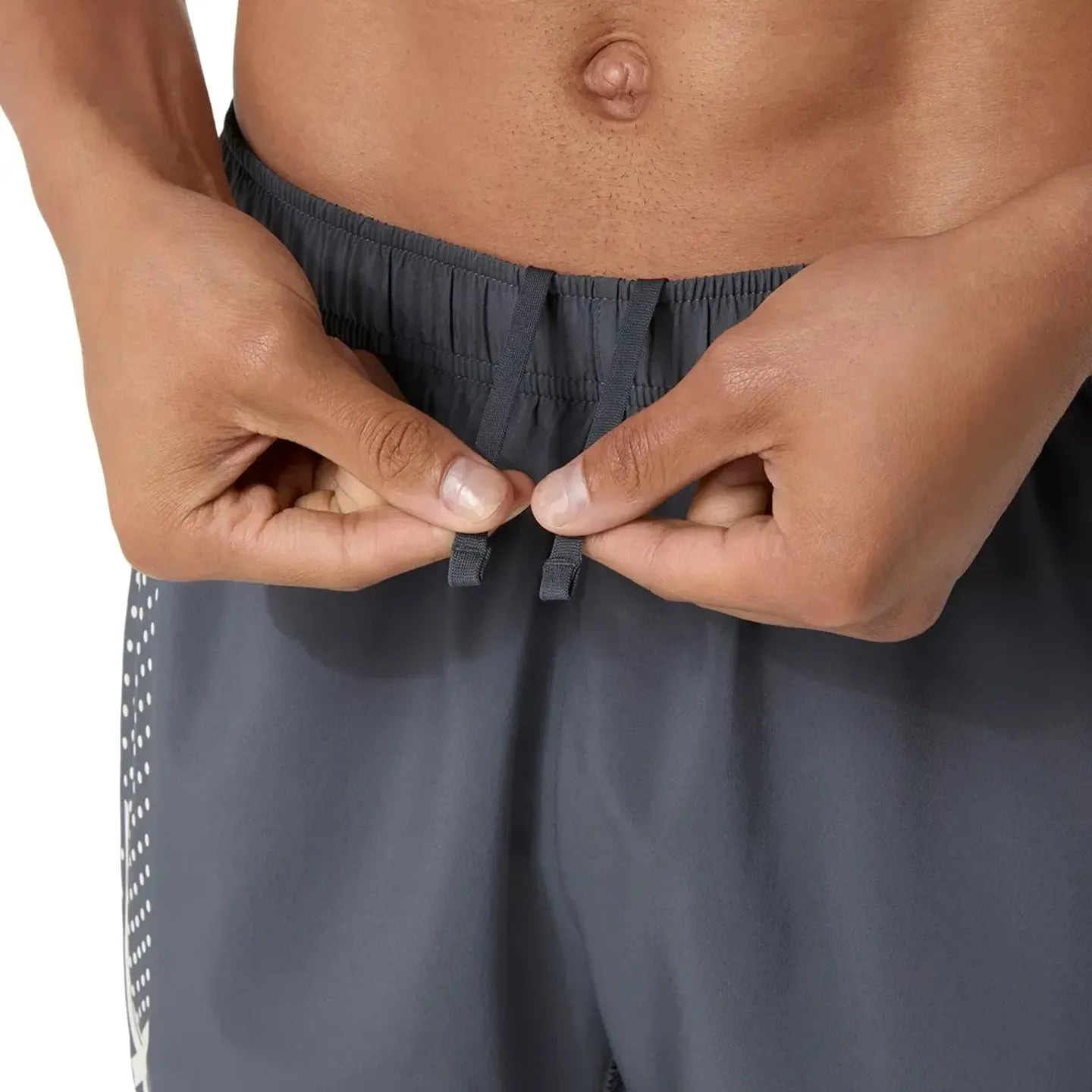 Gros plan sur les mains ajustant le cordon de serrage interne de la ceinture élastique du short ASIC