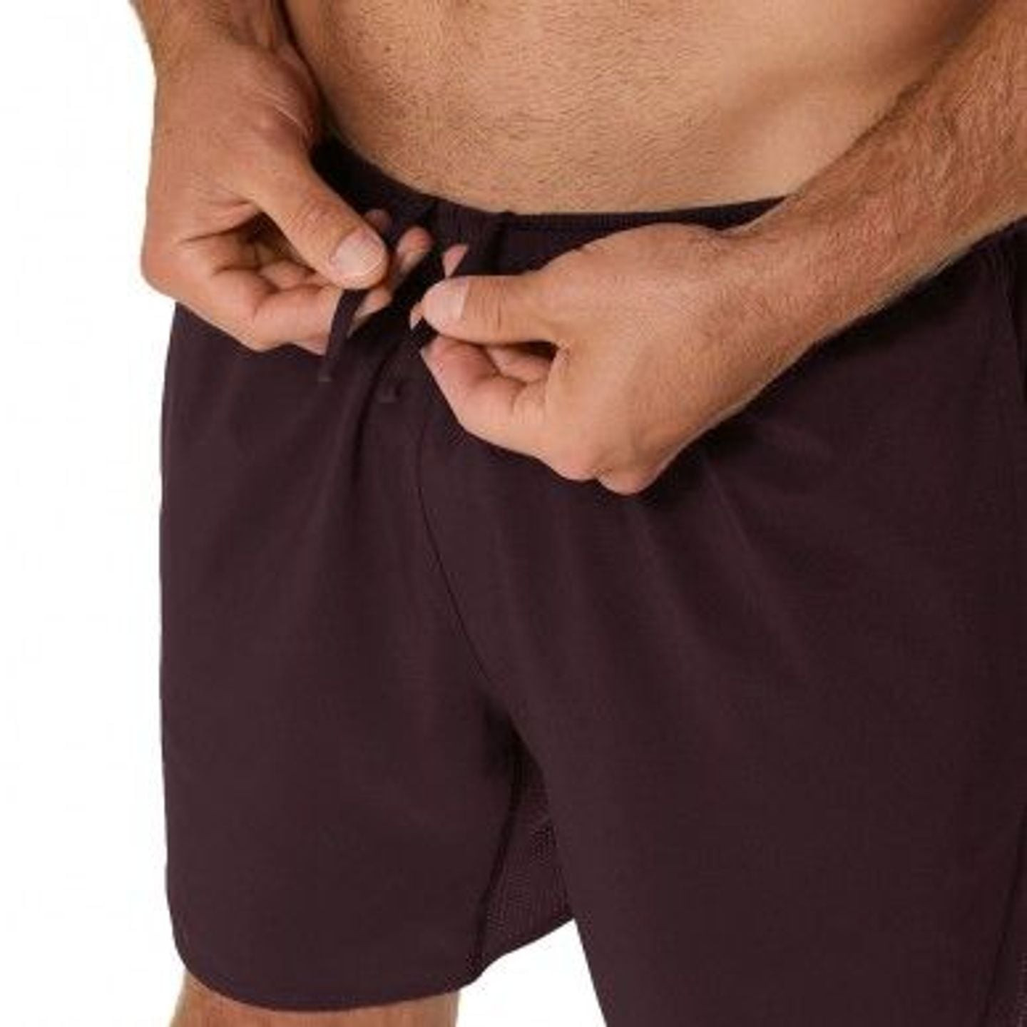 Gros plan sur des mains ajustant le cordon élastique de la ceinture du short ASICS Core 7 pouces fon