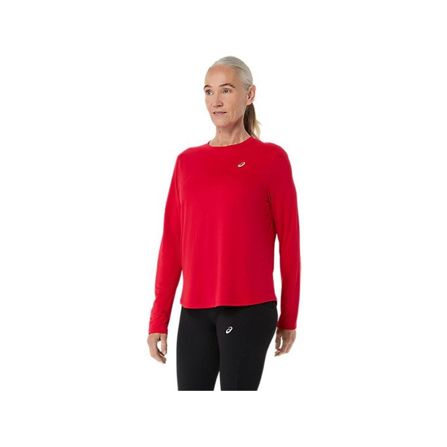 Vue de trois quarts avant d'une femme portant le ASICS CORE LS TOP rouge et un leggings noir