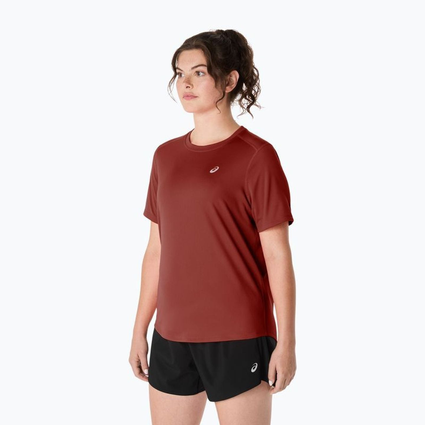 Vue de trois quarts du t-shirt ASICS Core SS Top rouge rouille porté avec un short de running noir