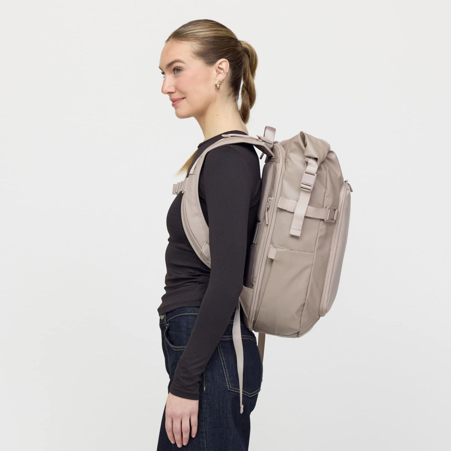 Vue de profil d'une femme portant le sac à dos rolltop Lisbon Pro Muted Rose sur le dos
