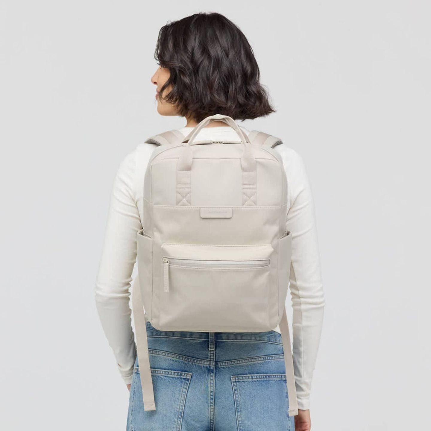 Femme portant le sac à dos Kapten & Son Bergen Pro Sandstone avec un haut à manches longues blanc et
