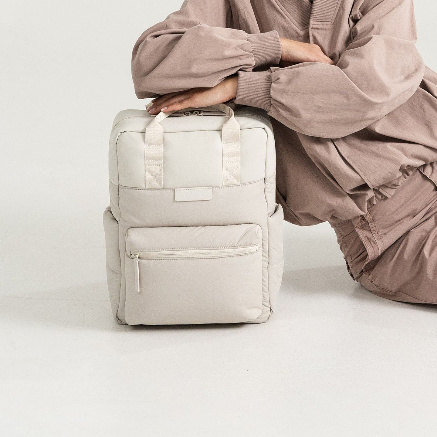Personne accroupie près du sac à dos Kapten & Son Bergen Cloud sable posé au sol dans un studio lumi