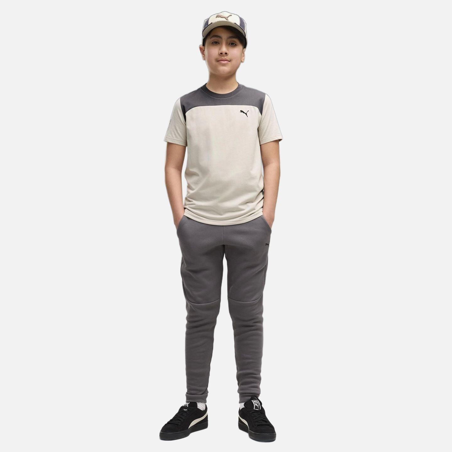 Adolescent en t-shirt beige et pantalon PUMA PUMATECH Elevated Pants gris Moody, mains dans les poch
