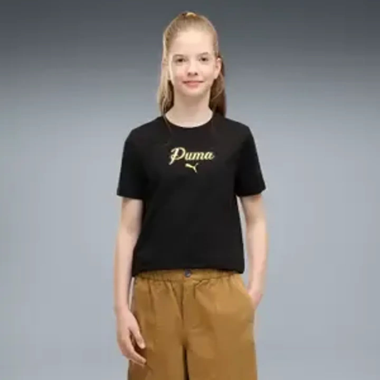Fille portant le t-shirt PUMA ESS Script Glitter Tee G noir avec logo doré, associé à un pantalon ma