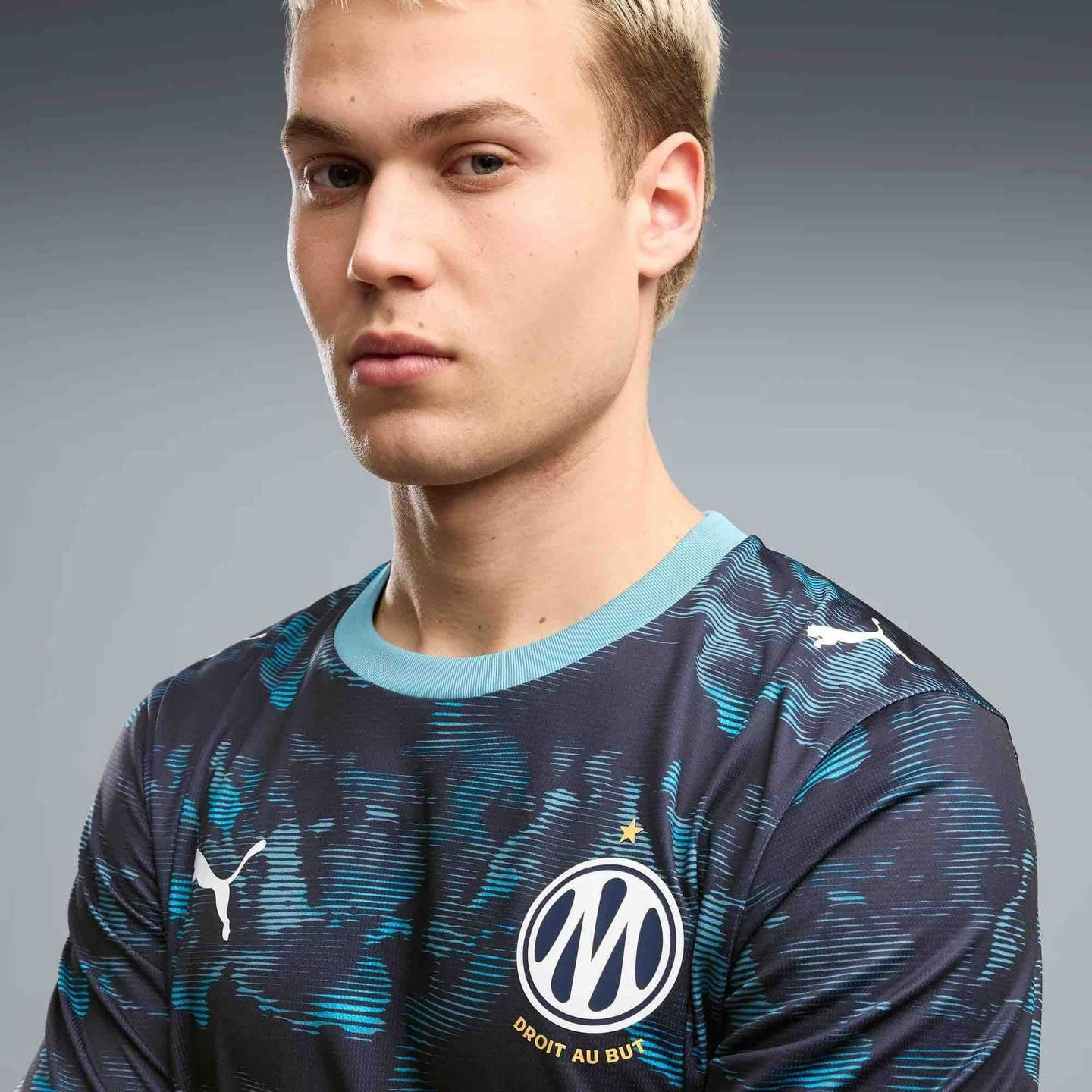 Gros plan sur un mannequin en maillot extérieur réplique OM 2026/27 bleu marine à col bleu clair