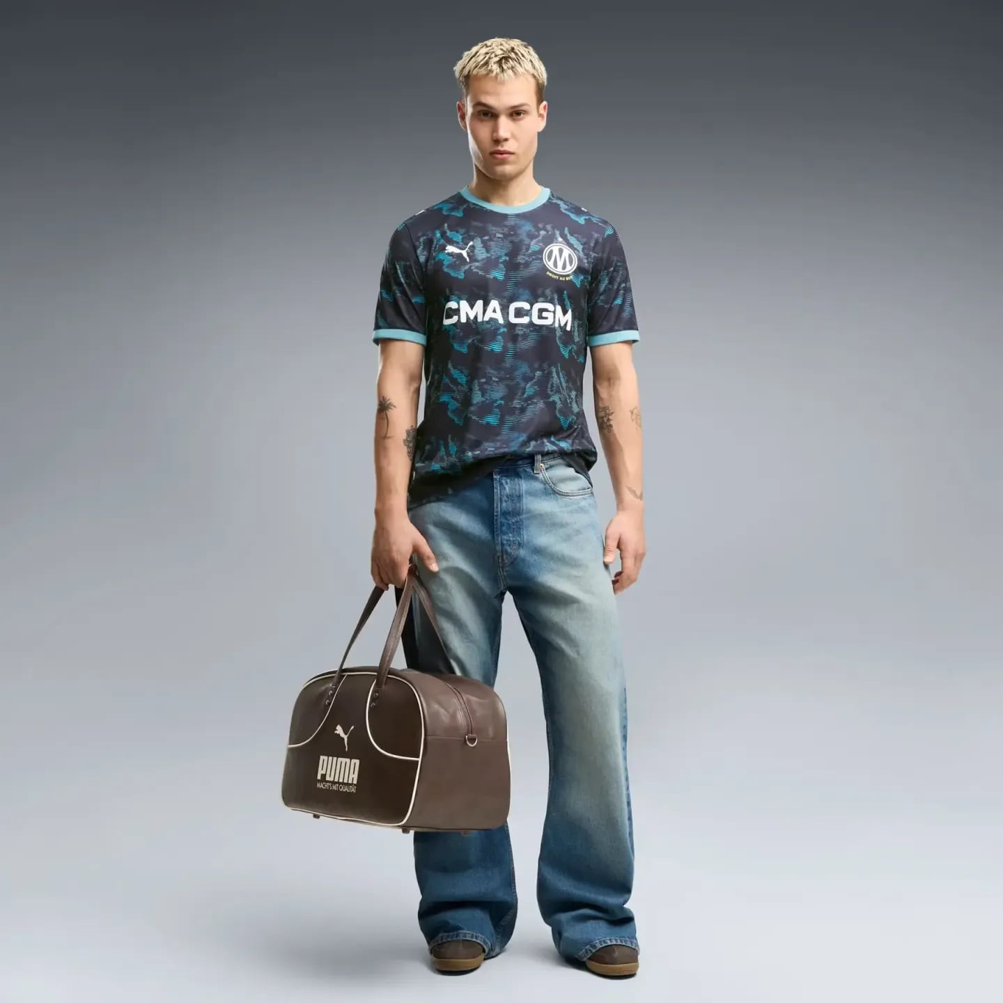 Mannequin en pied avec un sac PUMA marron et le maillot extérieur OM réplique 2026/27, en studio