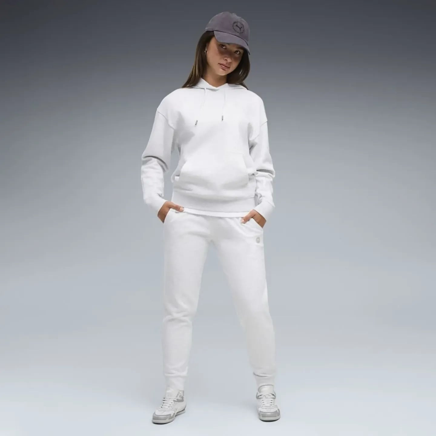 Femme en ensemble survêtement Puma Elevated FL CL blanc, casquette grise et baskets