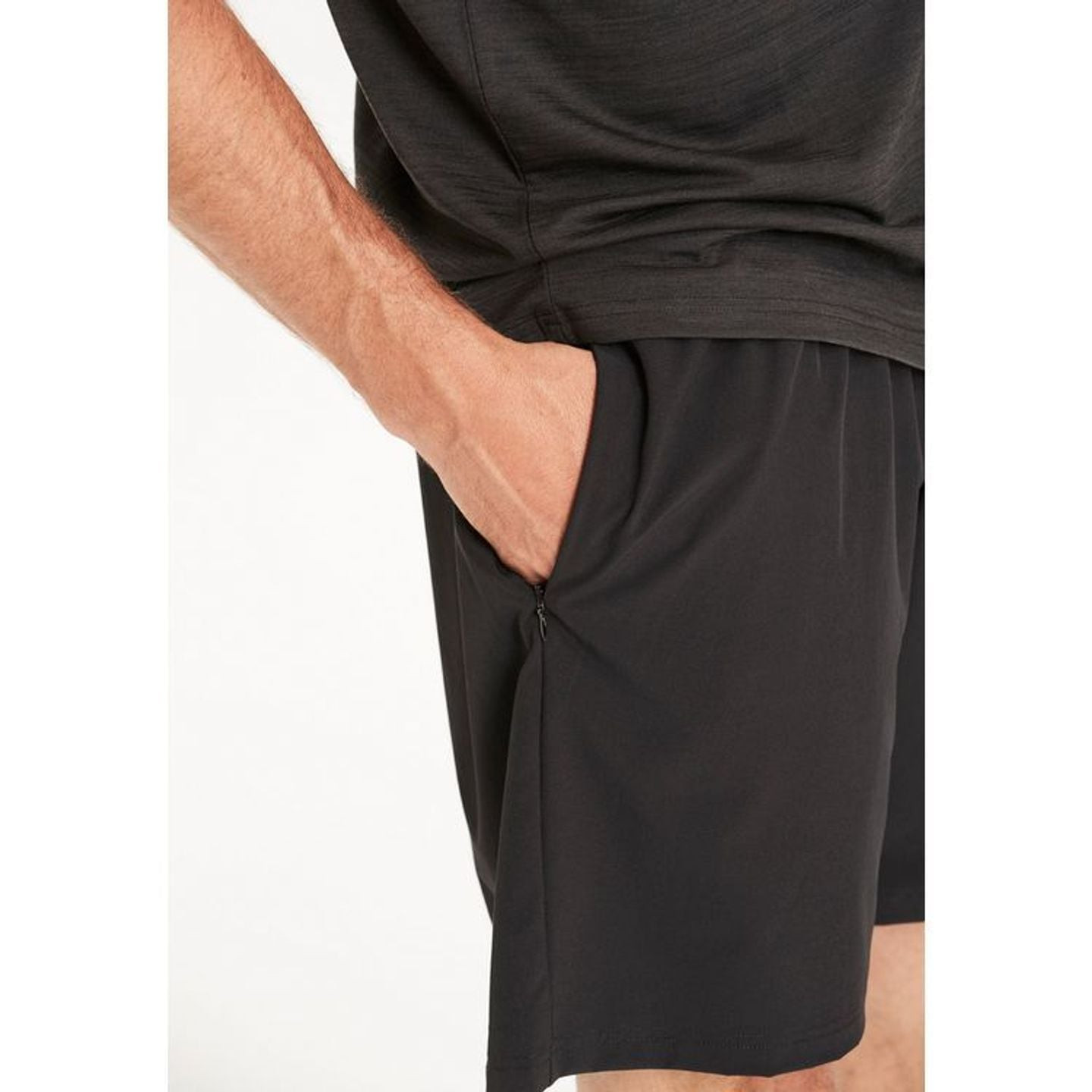 Une main glisse dans la poche latérale zippée du short de sport noir VIRTUS Forzer M pour homme