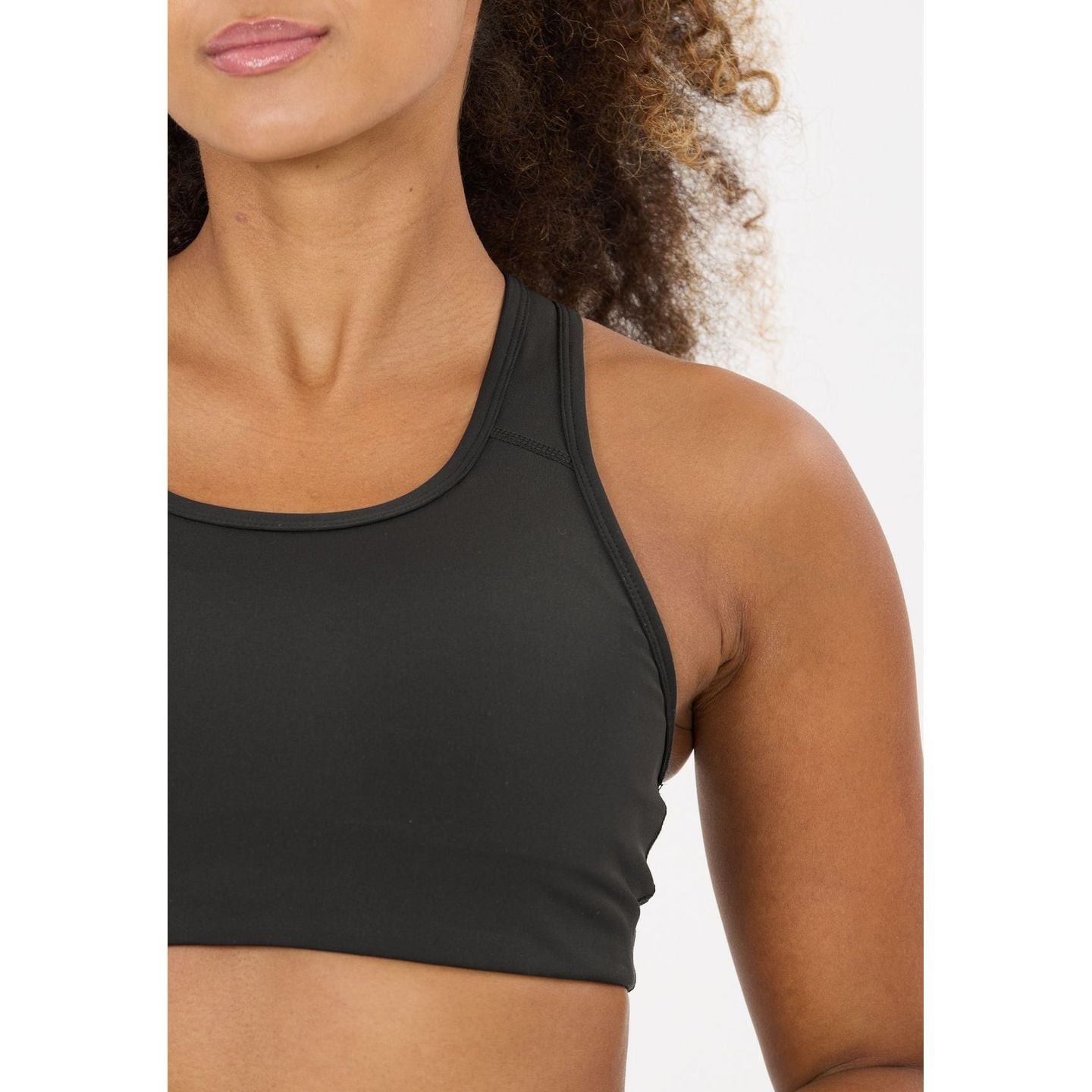 Gros plan sur l'encolure dégagée et les bonnets rembourrés de la brassière de sport noire Athlecia M