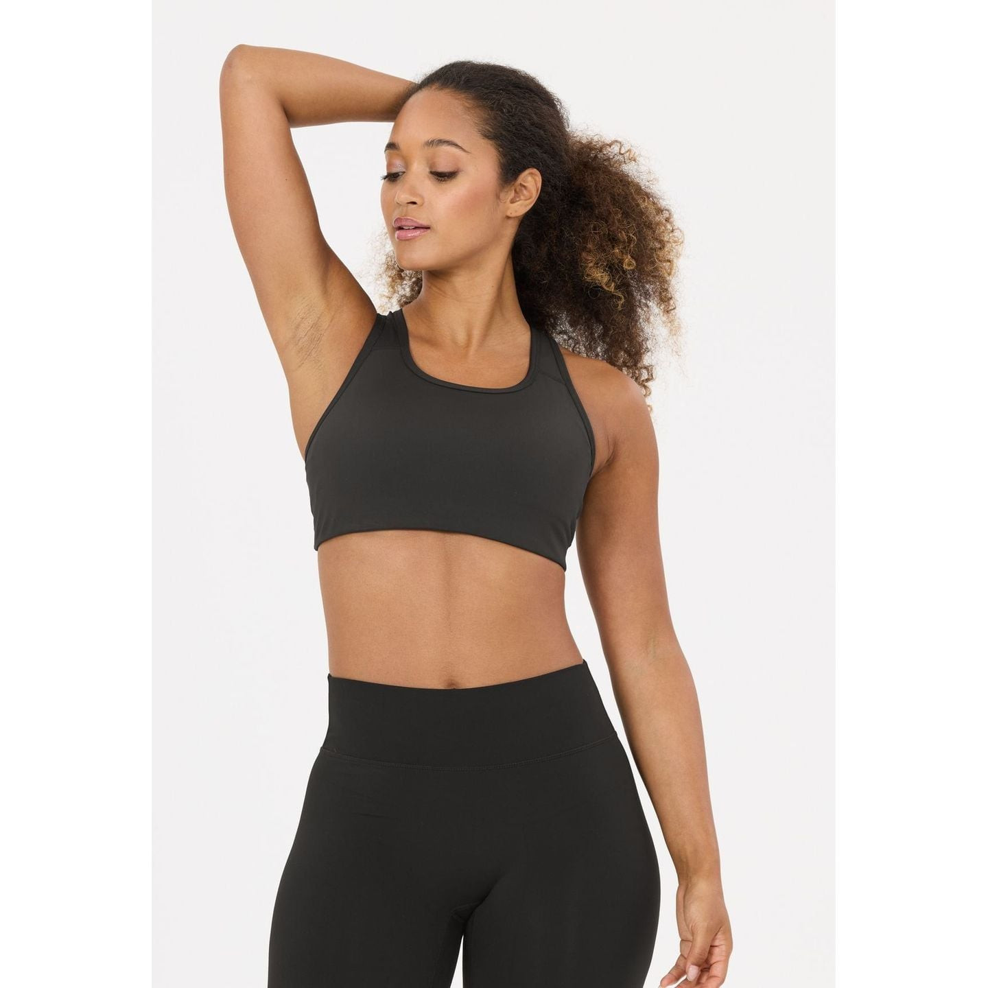 Modèle portant la brassière de sport Athlecia Myolie V2 noire avec leggings taille haute assortis, v