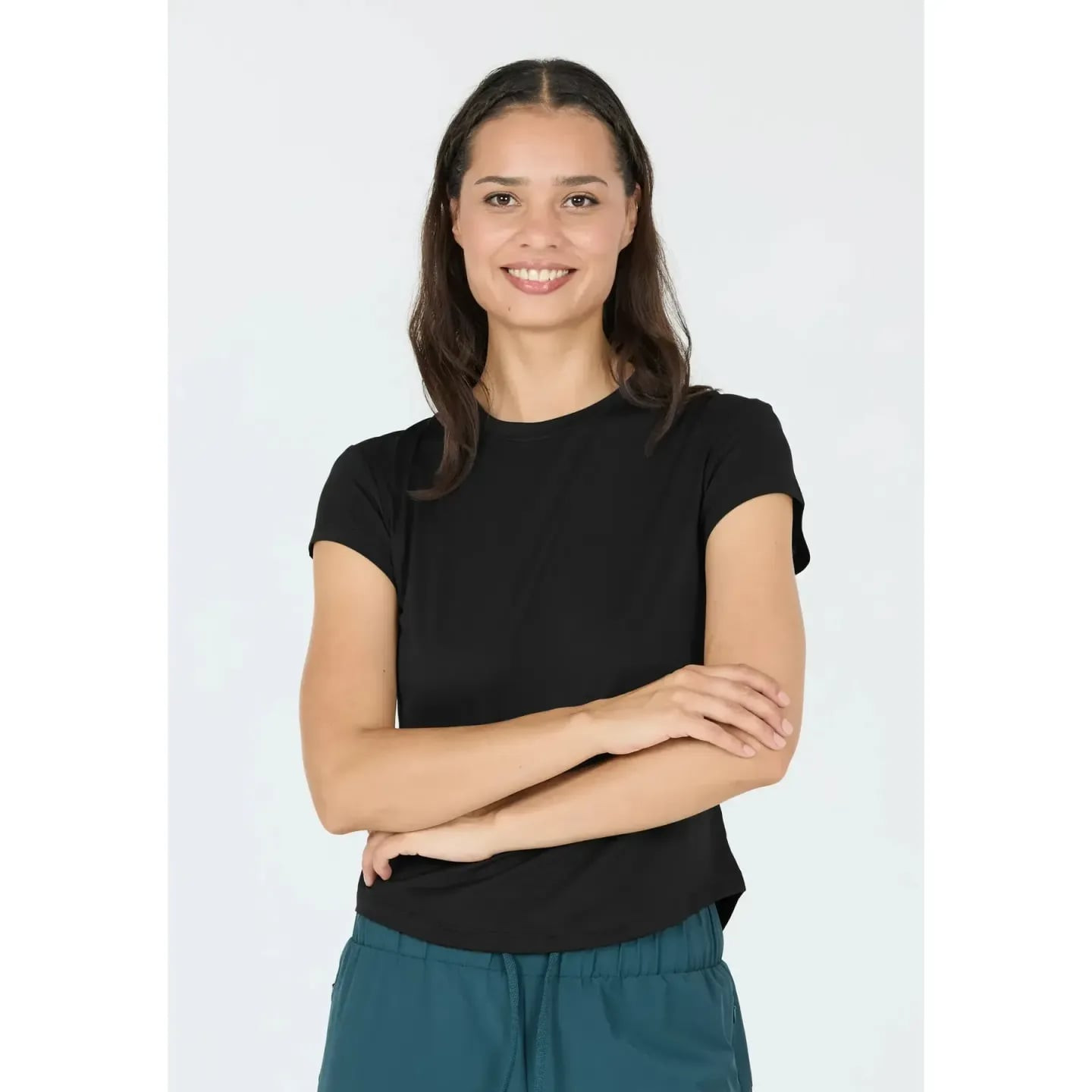 Femme souriante en t-shirt d'entraînement Athlecia Doja noir à manches courtes, bras croisés
