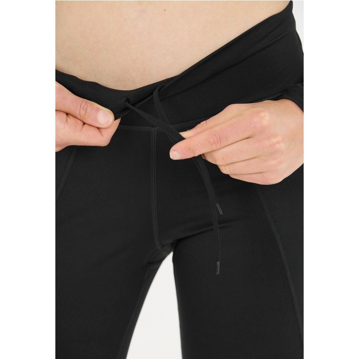 Gros plan sur des mains ajustant le cordon interne de la taille haute du TAROLE W TIGHTS noir