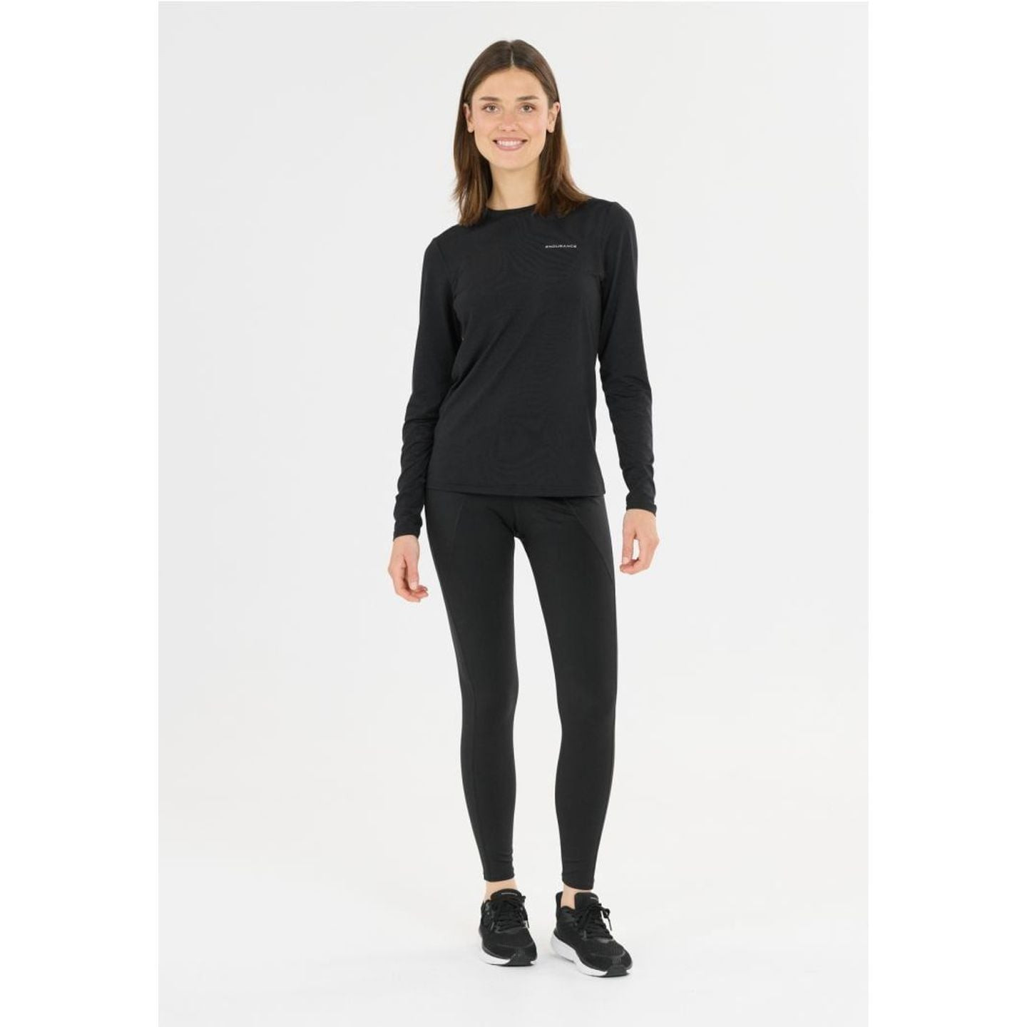 Femme souriante portant un haut manches longues noir et un legging TAROLE W TIGHTS, vue de face en p