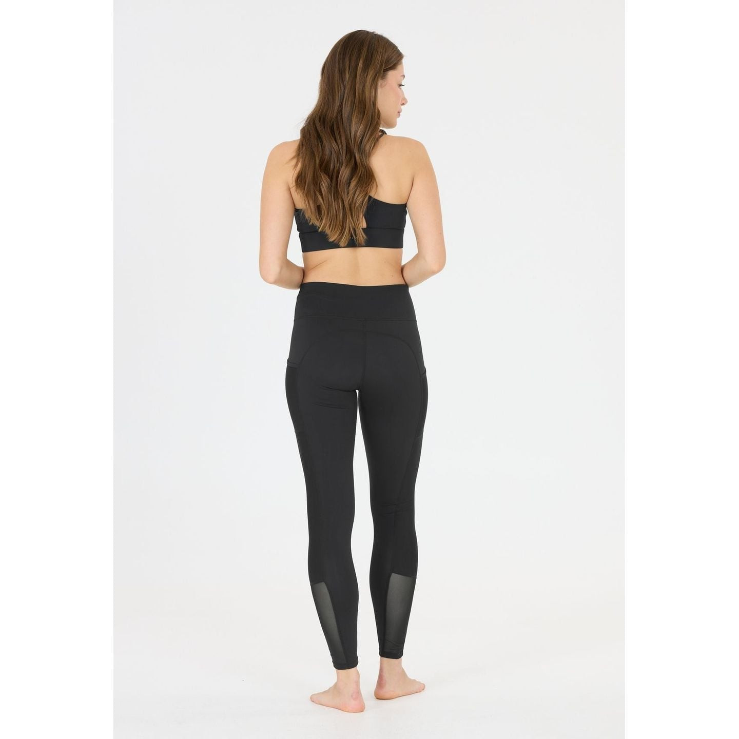 Photo lifestyle : femme active portant l'Athlecia Collant De Sport Ajusté Emissy Long Taille Mi-Haut