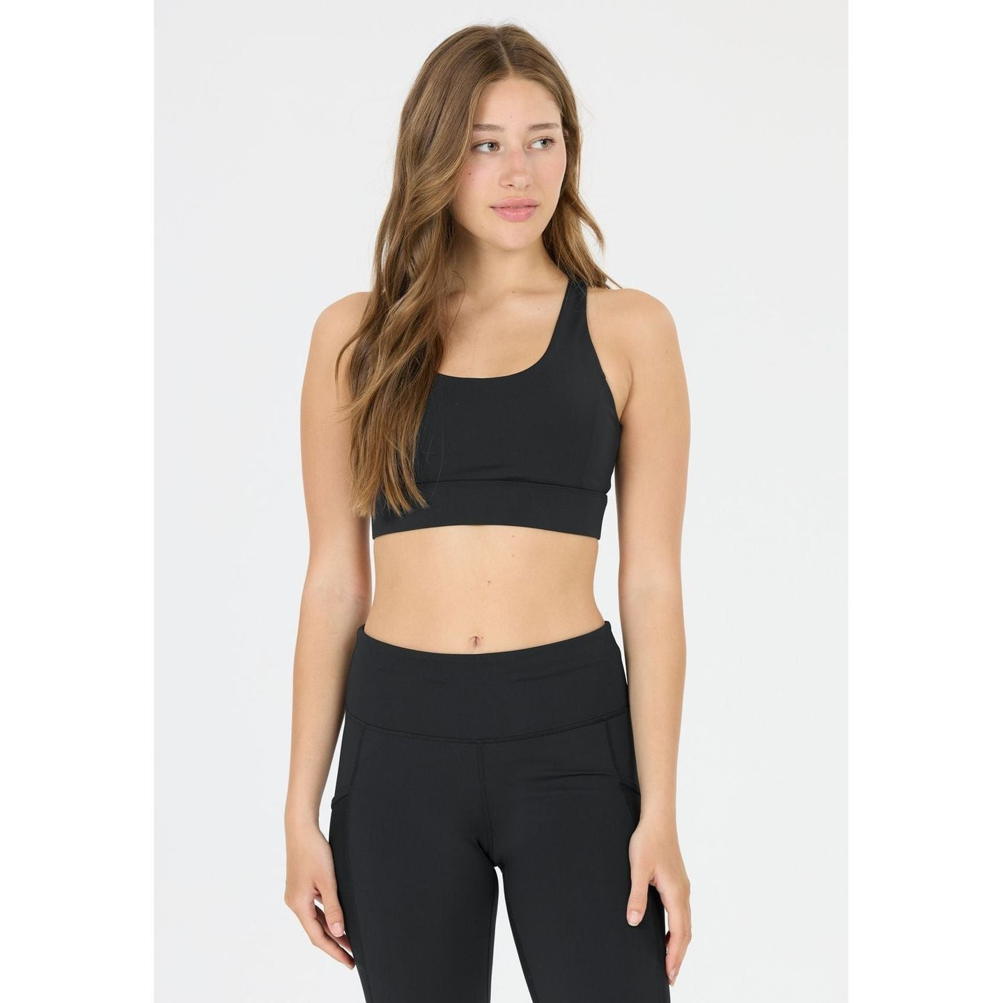 Mannequin portant la brassière Athlecia DIRENNA noire et legging noir assorti, vue de face sur fond 
