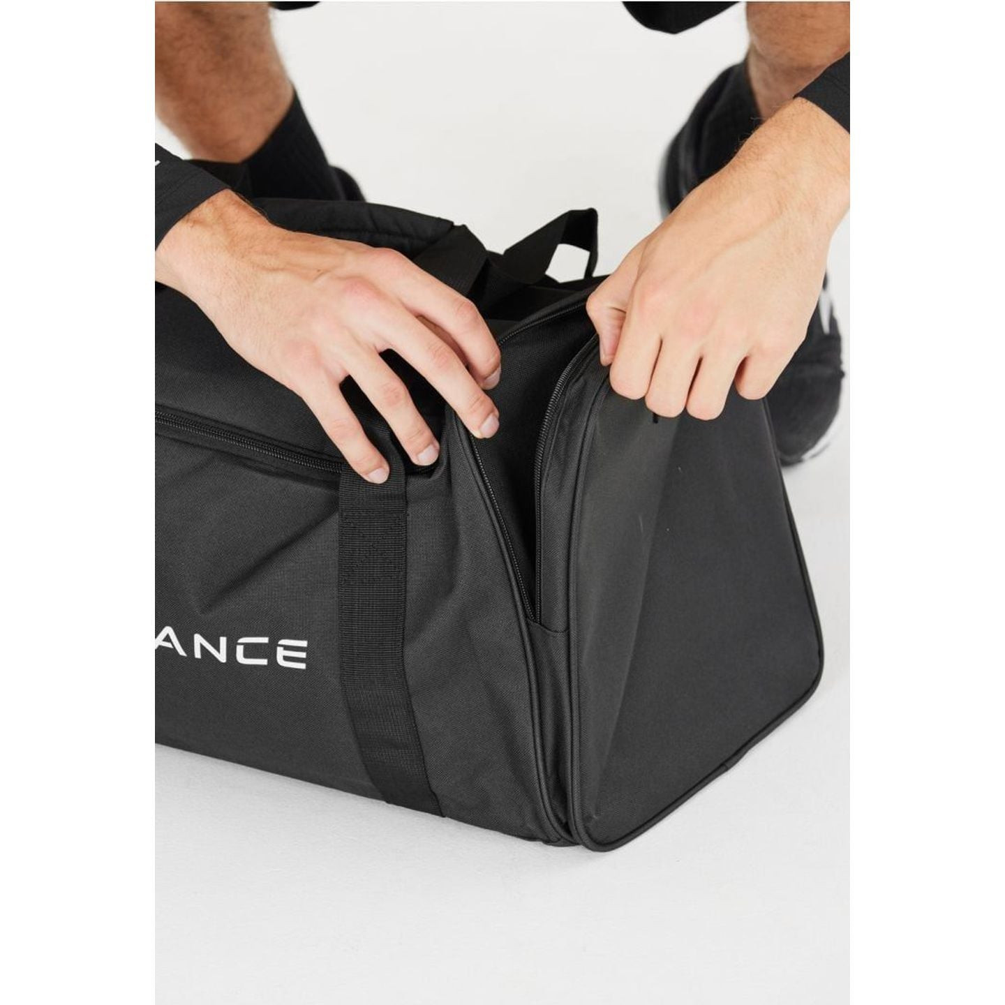 Mains ouvrant le compartiment latéral zippé du sac de sport Lanakila 40 L noir