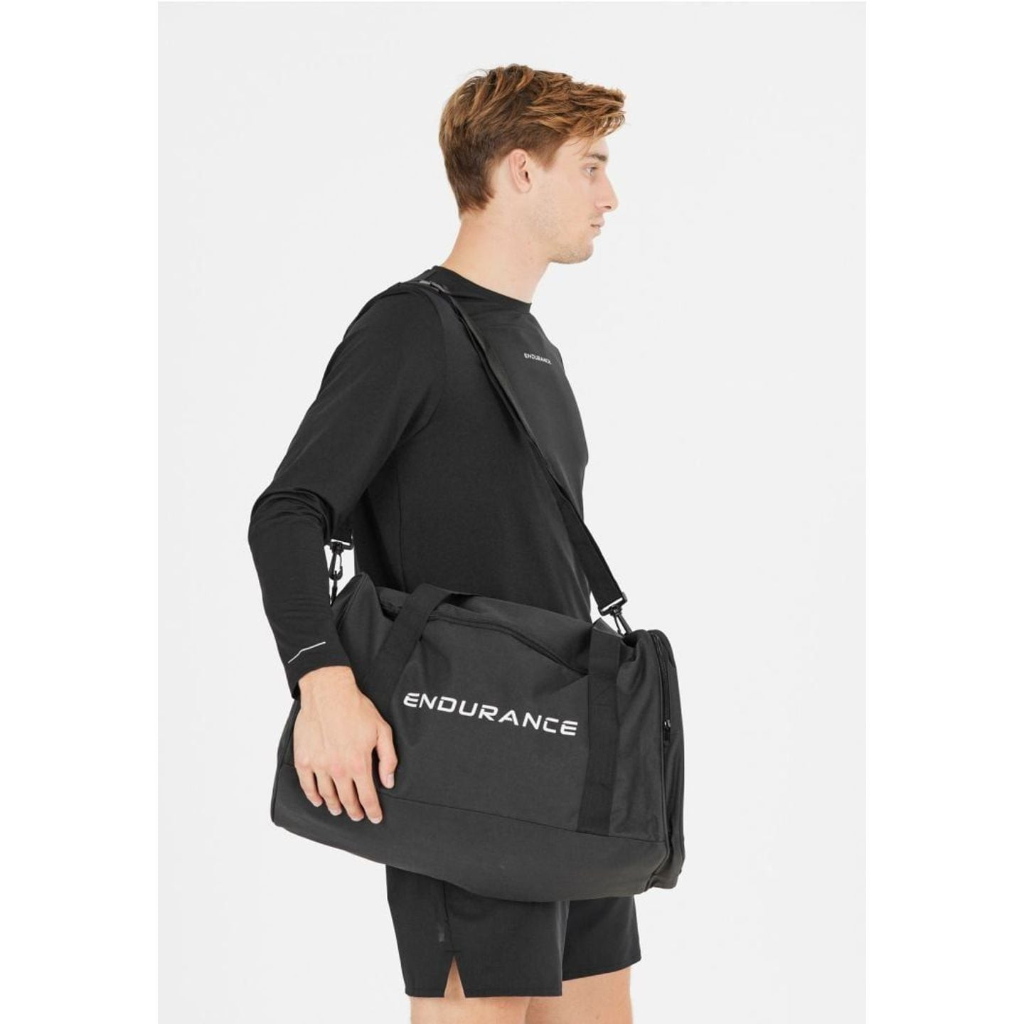 Un homme en tenue de sport noire porte le sac de sport Lanakila 40 L à l’épaule