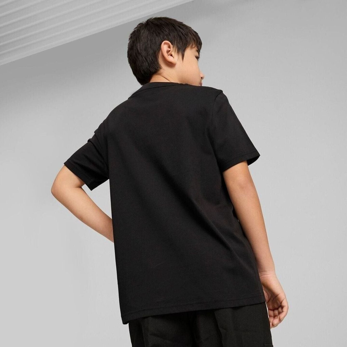 Vue de dos d'un jeune mannequin portant le t-shirt noir PUMA ESS No. 1 Logo Tee B en studio