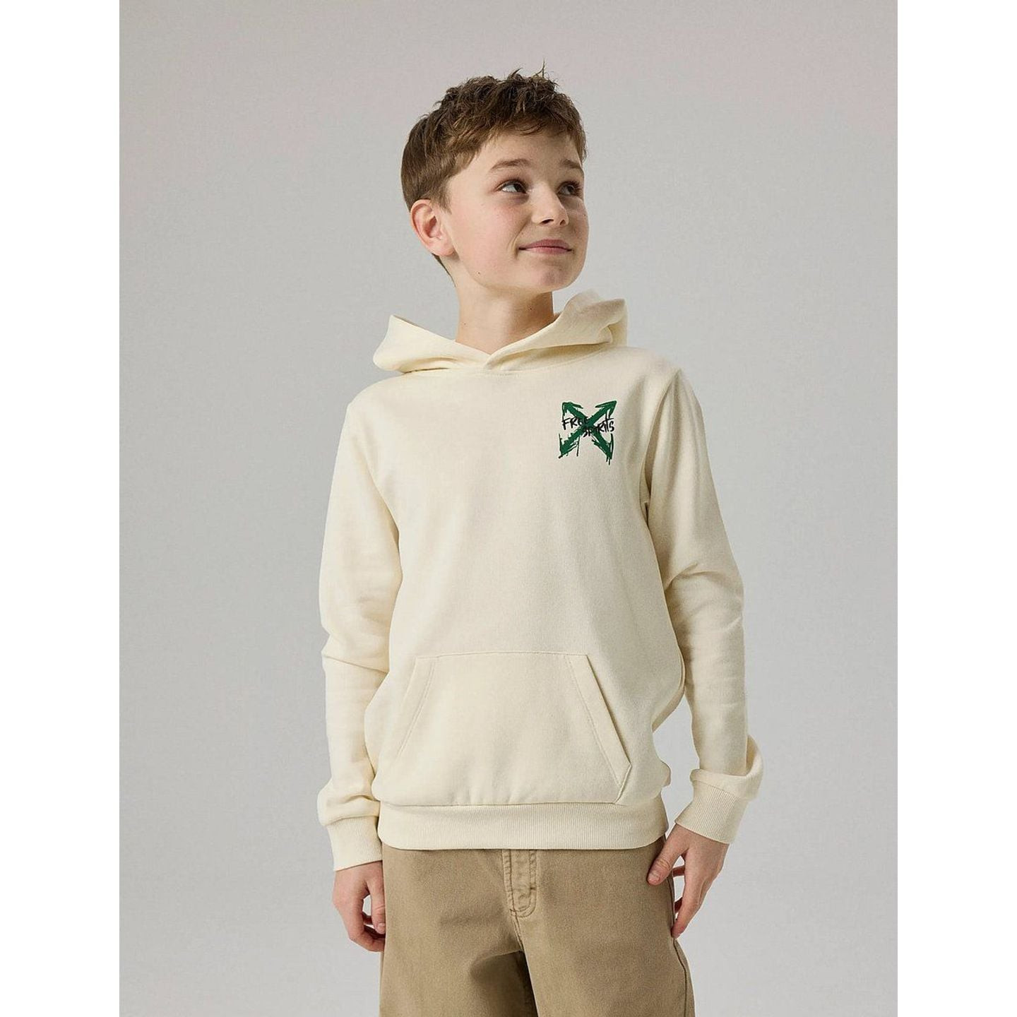 Garçon portant un sweat à capuche blanc cassé avec petit X vert imprimé sur la poitrine et poche kan