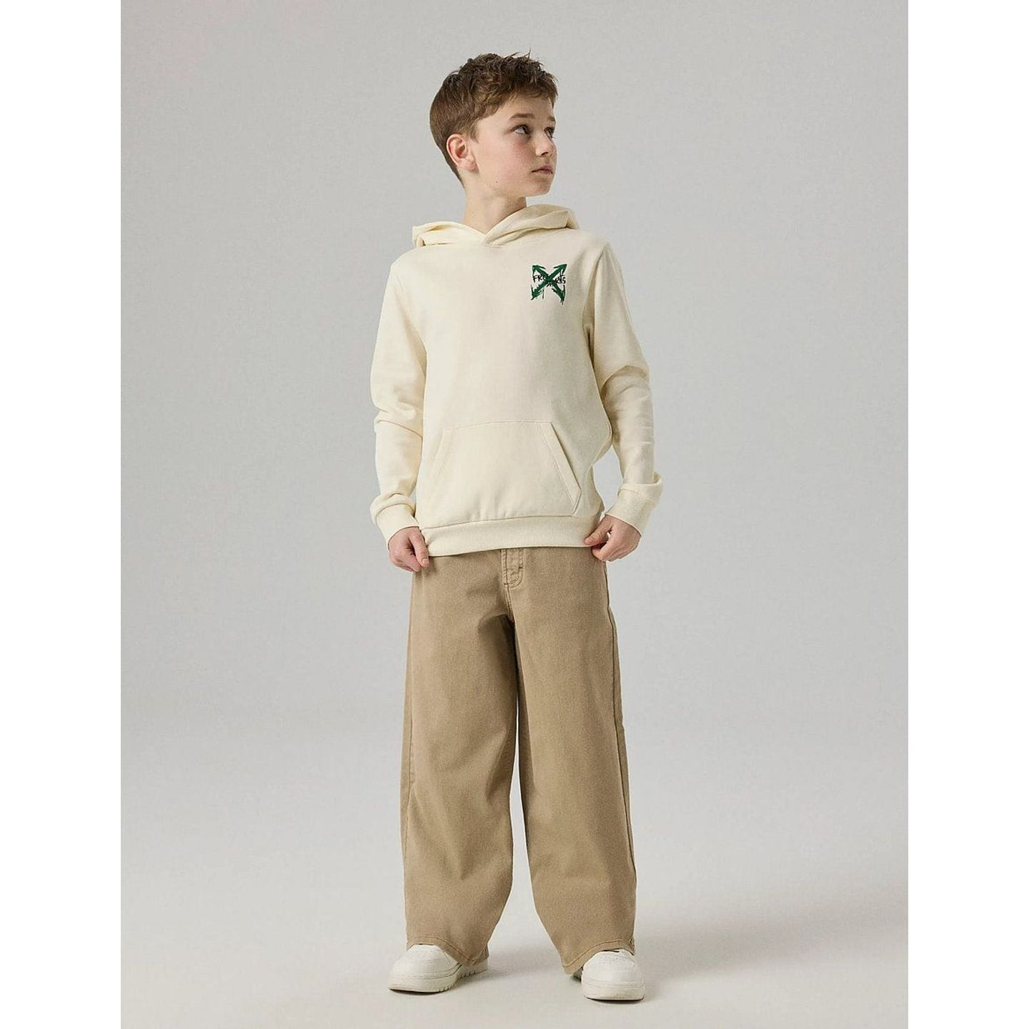 Plan pied d'un garçon portant un sweat à capuche NAME IT crème et un pantalon large beige
