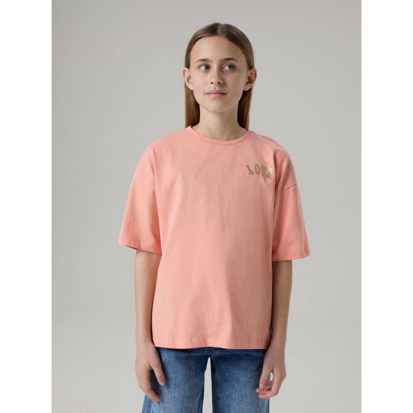 Fille souriante portant le t-shirt Name It à manches courtes coupe ample imprimé glitter en extérieu