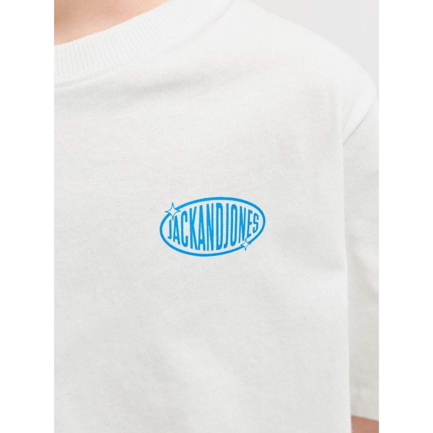 Gros plan sur le petit logo ovale bleu JACKANDJONES imprimé sur la poitrine du t-shirt blanc junior.