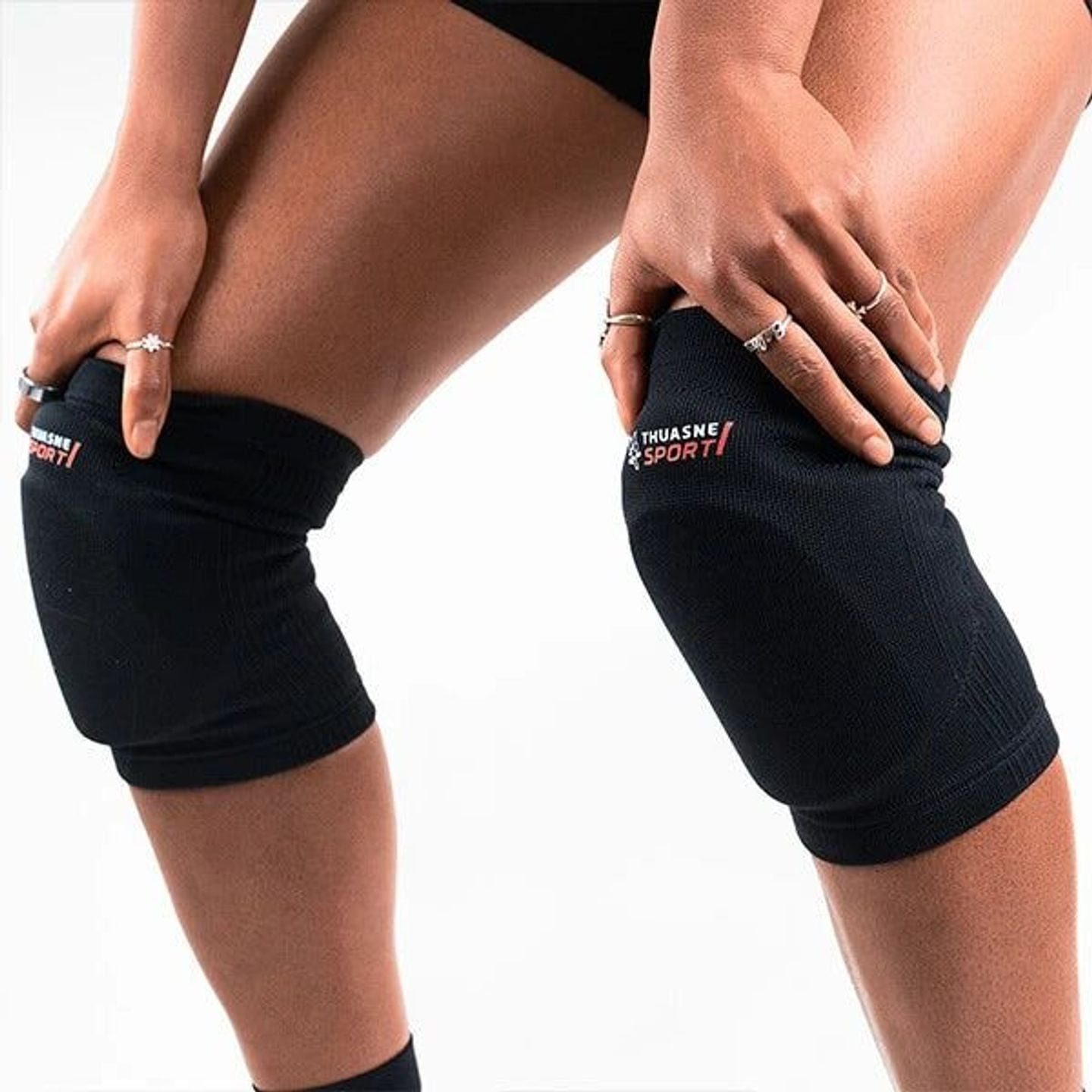 Athlète féminine portant une paire de genouillères noires Thuasne Sport, mains posées sur les genoux
