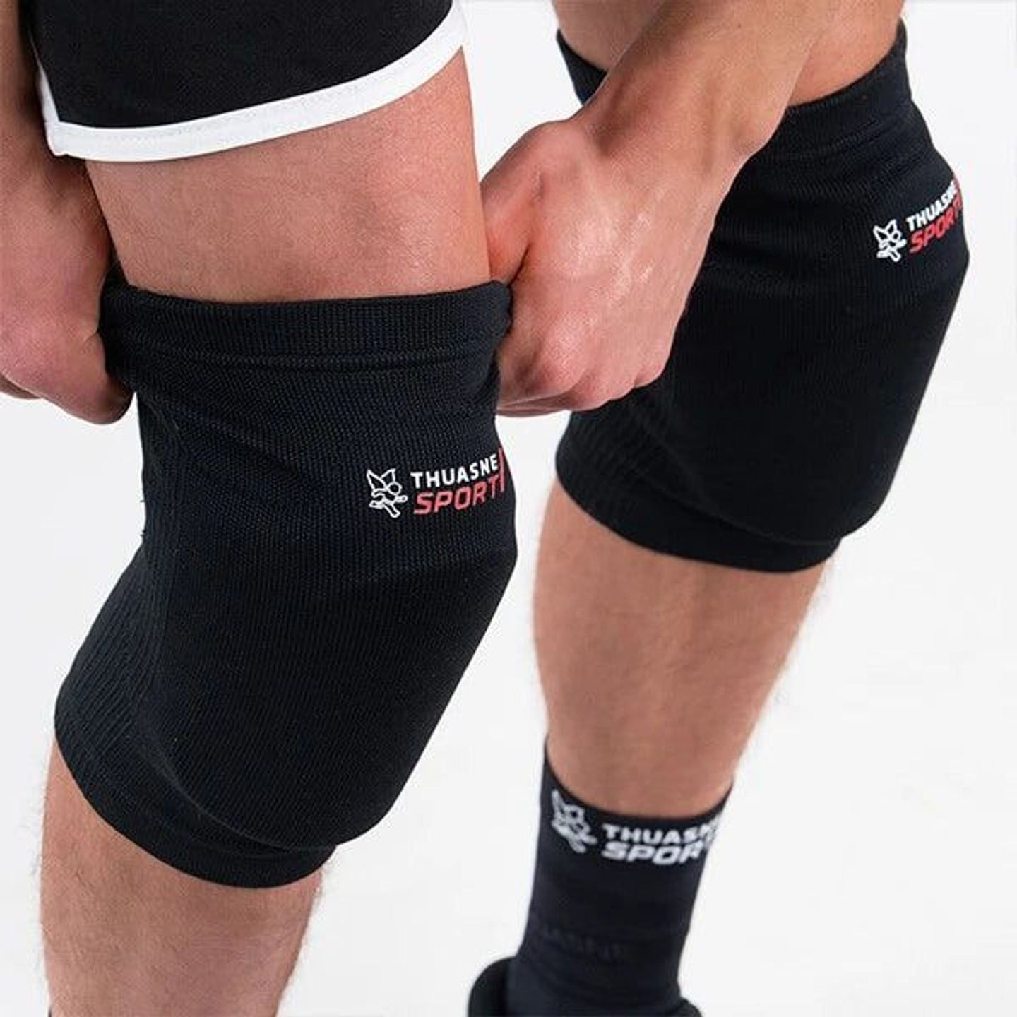 Athlète enfilant une genouillère noire Thuasne Sport avant un match