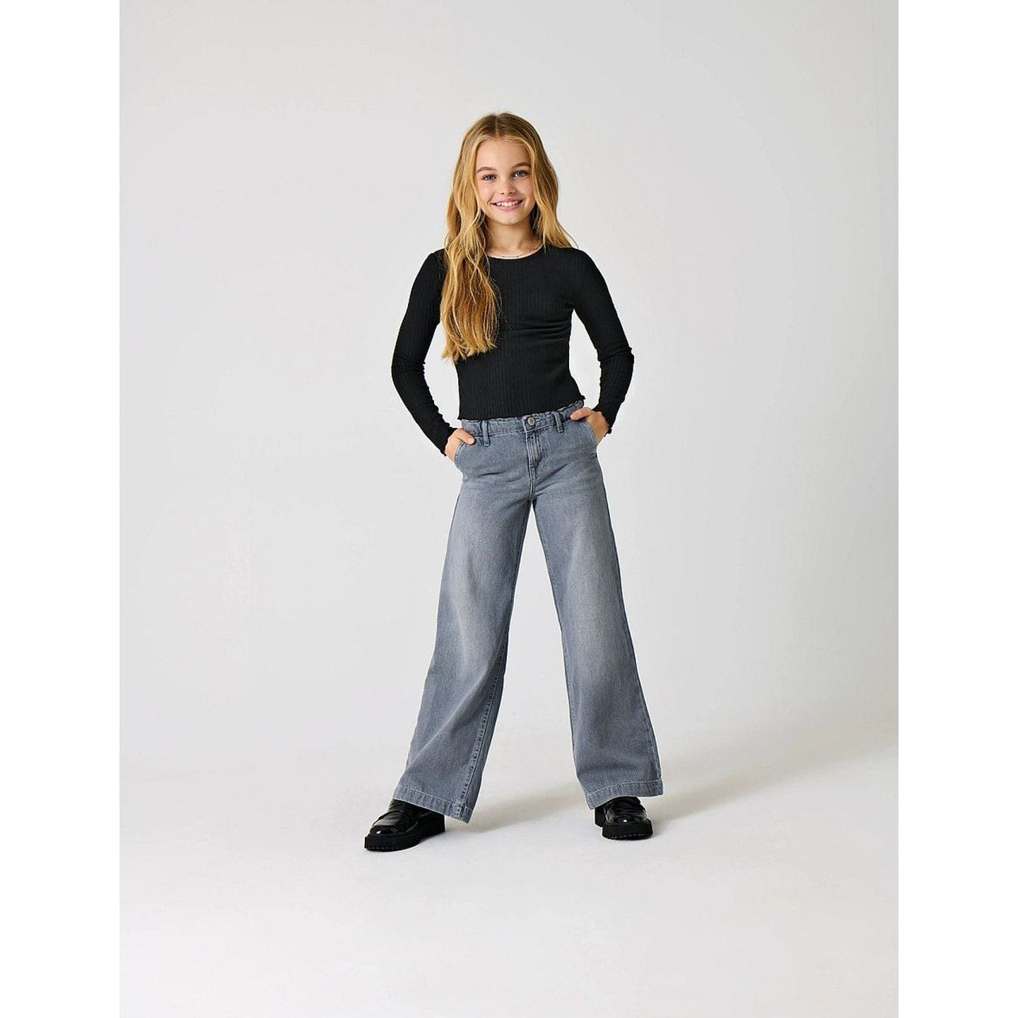 Jeune fille portant un jean large KOGCOMET gris, haut et chaussures noirs, en studio lifestyle